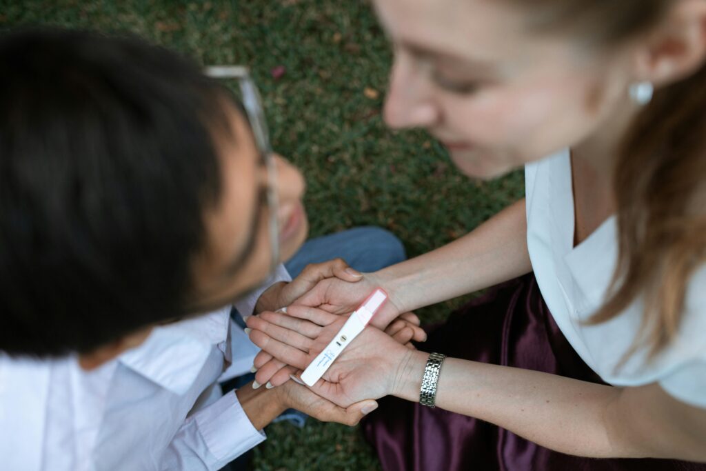 Woman holding a pregnancy test kit in front of a man